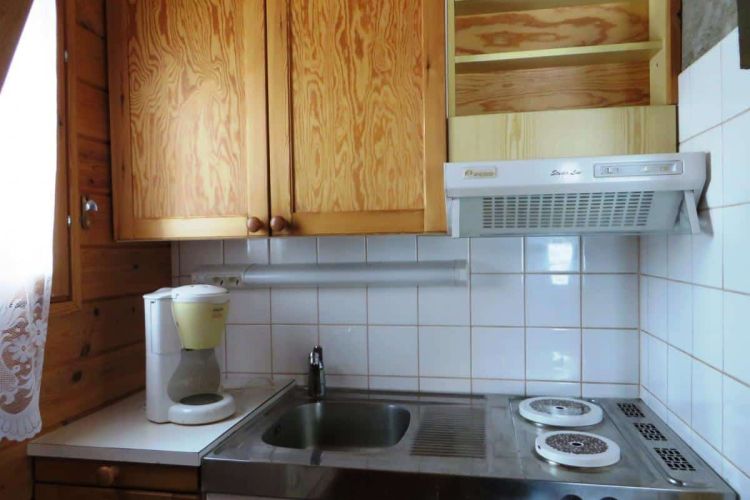 Keittiö tiskialtaalla, kahvinkeittimellä ja kahdella keittolevyllä.