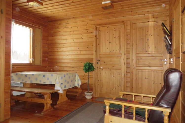Pirttikalusto ja nojatuoli valoisassa oleskelutilassa.